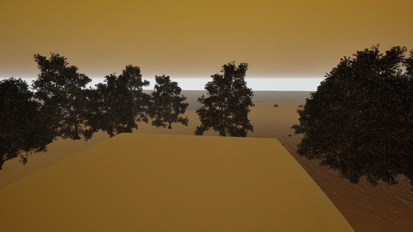 A sandy plateau seen against a hazy golden-yellow sky, silhouetted trees along both edges, scattered rocks, and a pale strip of water on the horizon.